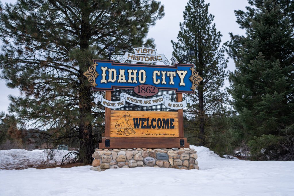 Welcome to Idaho City sign with trees and snow