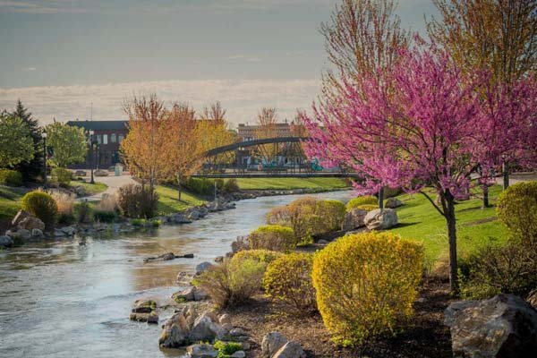 Scenic view of Indian Creek Plaza in Caldwell Idaho with blooming trees and pedestrian bridge